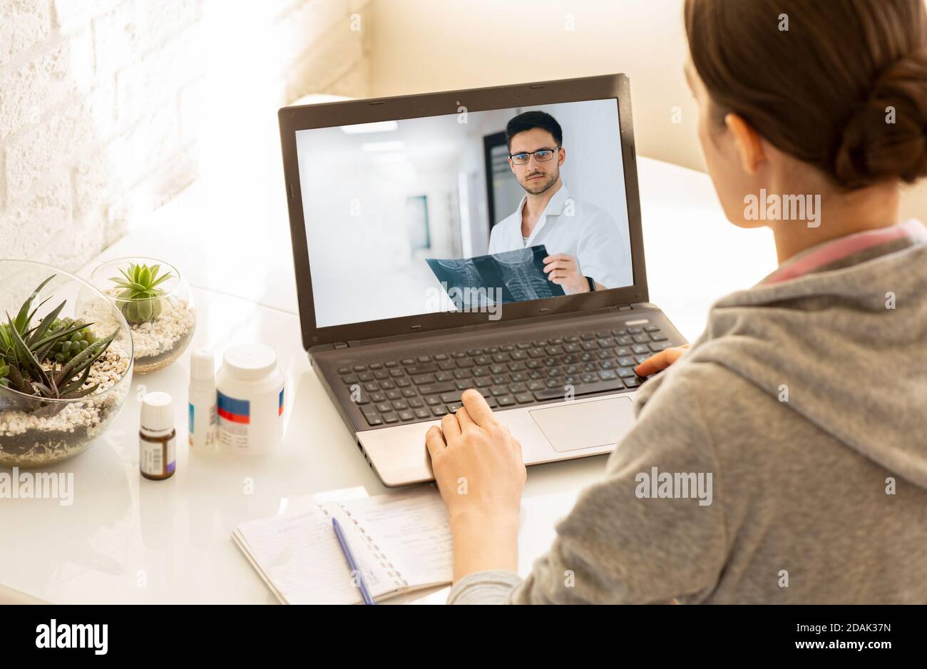 Frau, die bei einer Online-Konsultation mit ihrem Hausarzt zu Hause sitzt. Medizintechnik, Videochat mit einem Arzt Stockfoto