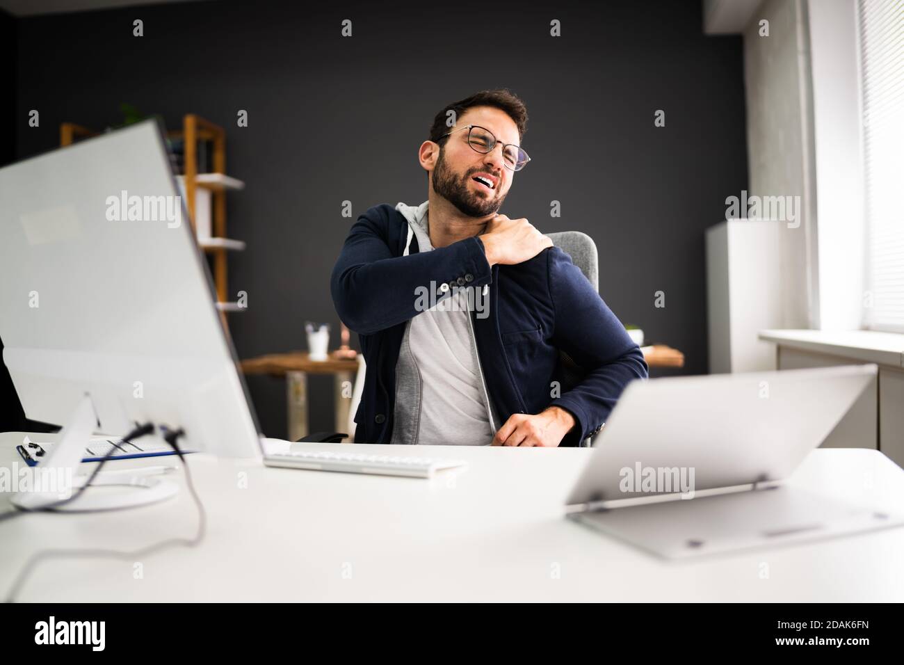 Junger Mann Mit Angespannten Schulterschmerzen. Problem Mit Der Bürohaltung Stockfoto
