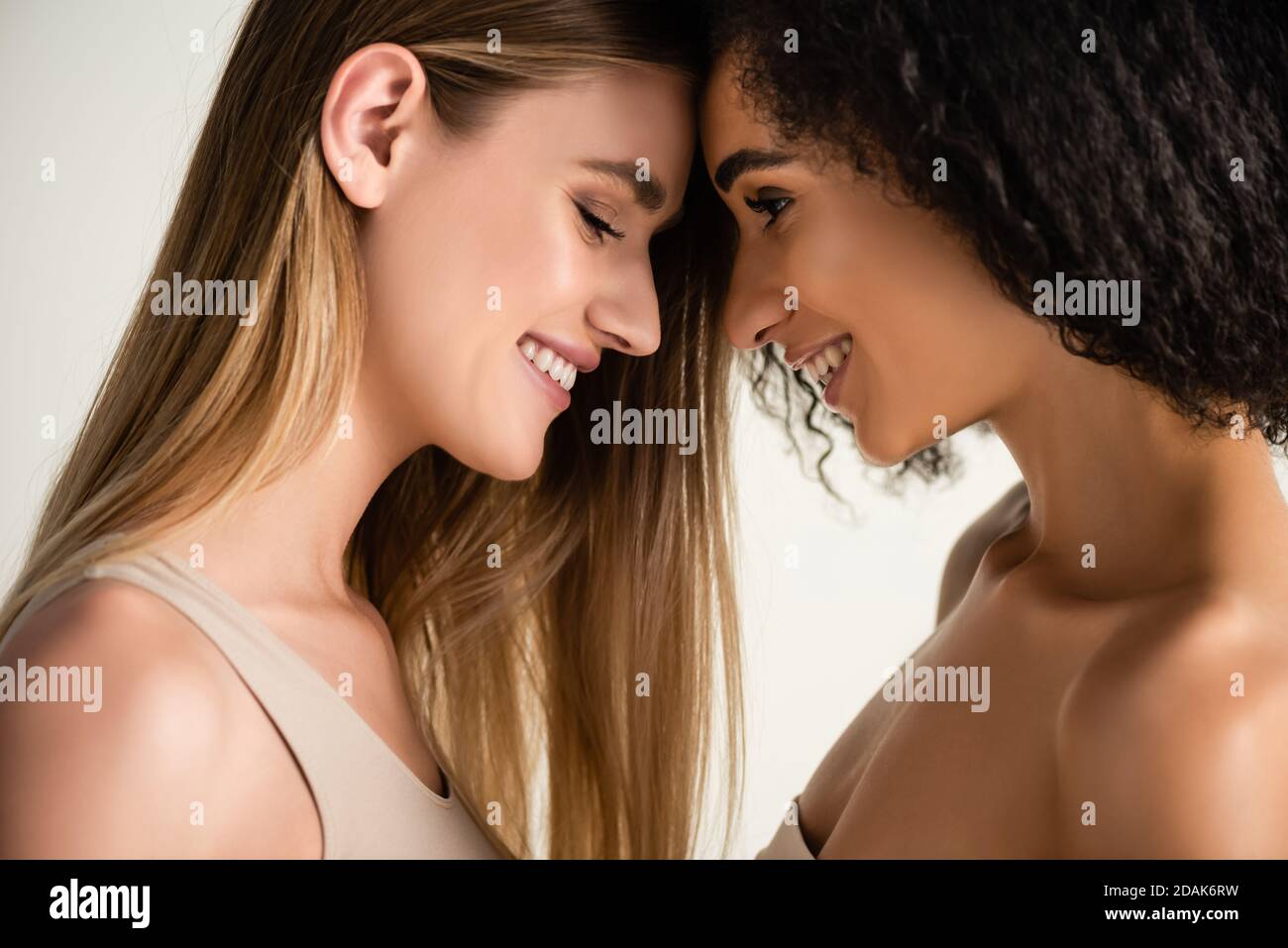 Seitenansicht von fröhlichen und jungen multikulturellen Modellen isoliert auf Weiß Stockfoto