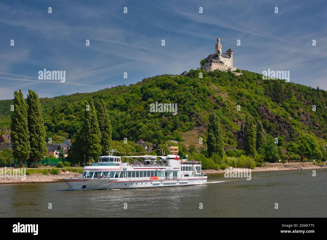 Eine Vergnügungskreuzfahrt auf dem Rhein mit einem Hintergrund von Bäumen auf dem Flussufer und Hügel gekrönt von einem schönen weiß ummauerten Schloss, Deutschland Stockfoto