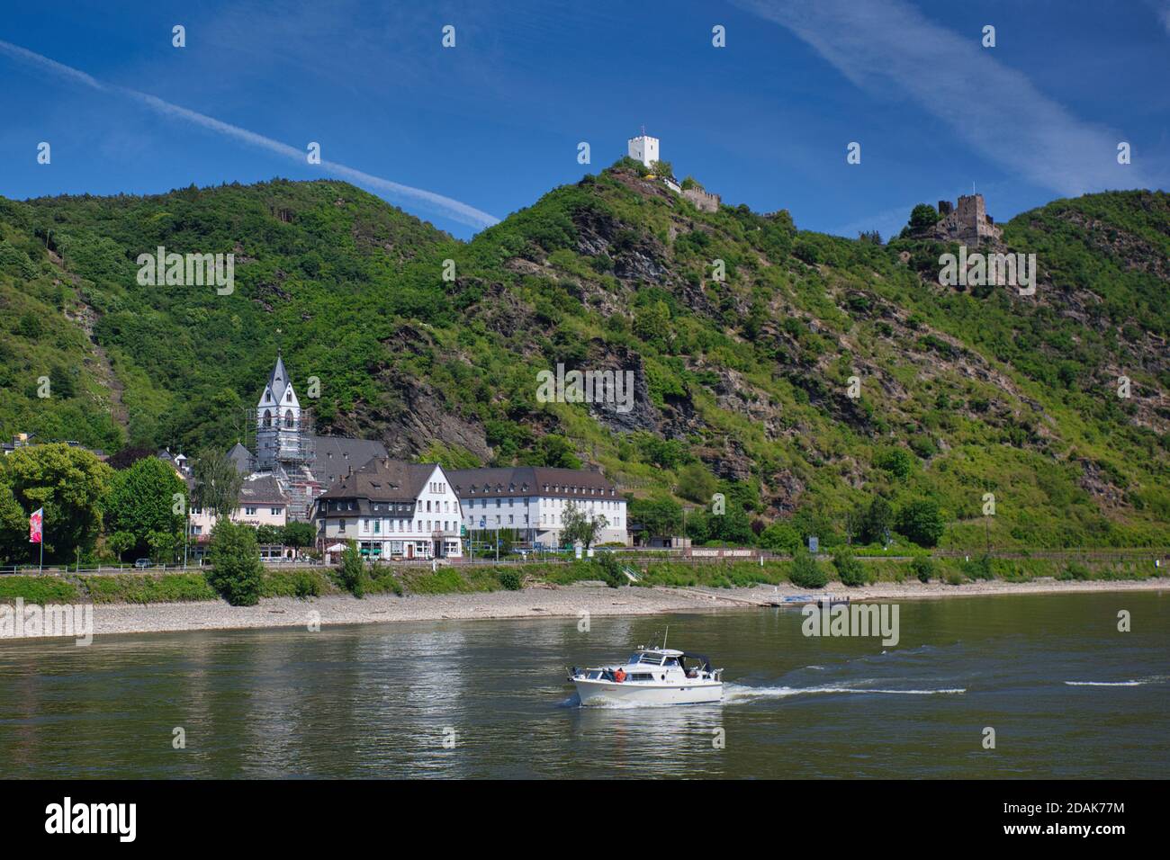 Eine Stadt am Rhein mit einem Schloss auf dem Hügel dahinter & kleines Motorboot im Vordergrund, gegen einen blauen Himmel. Der Rhein, Deutschland Stockfoto