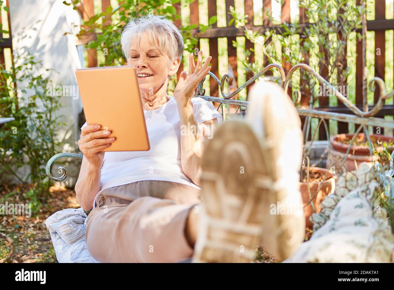 Rentner lächelnde ältere Frau Video-Chat online auf Gartenbank Im Sommer Stockfoto
