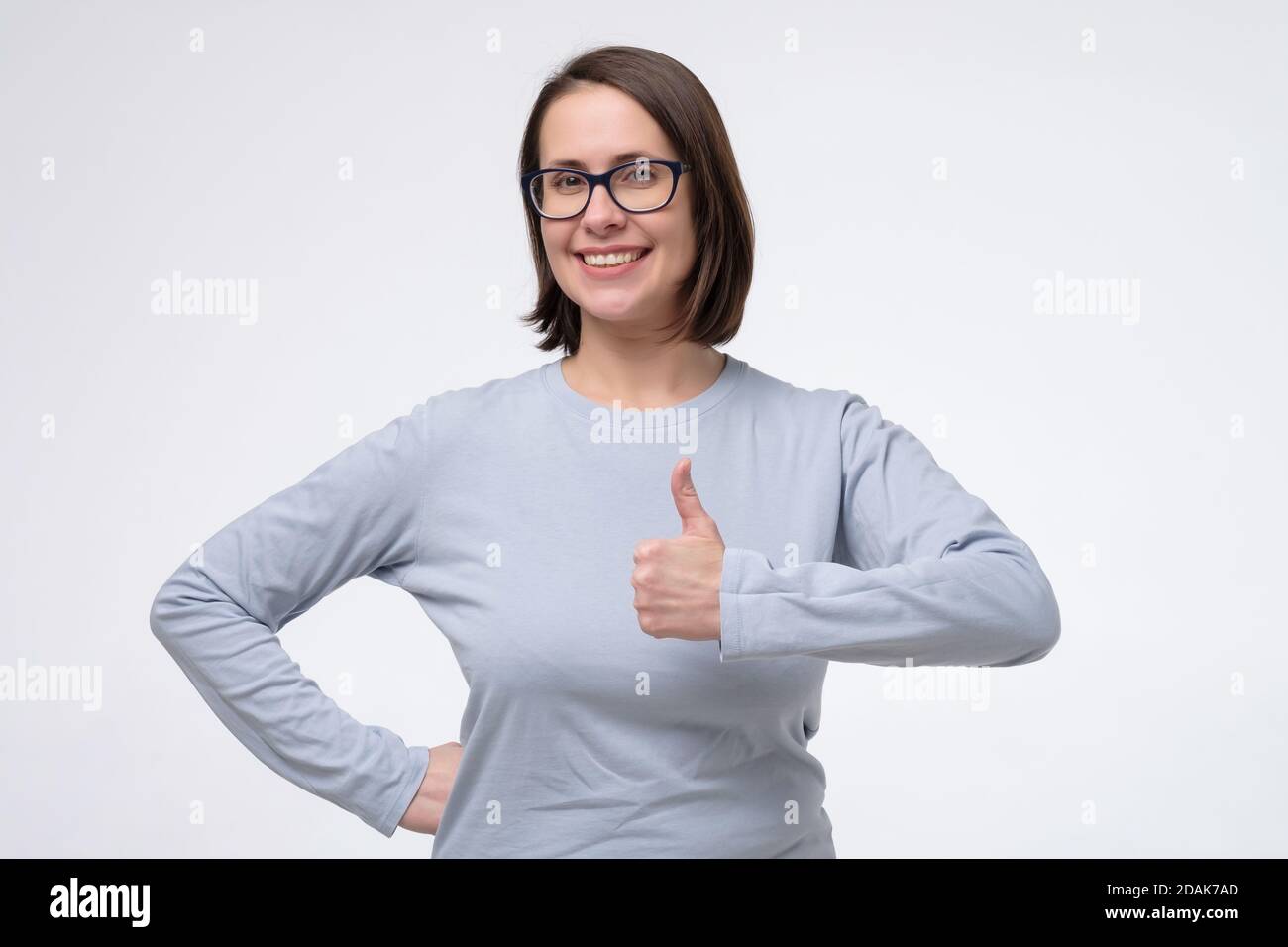 Hübsche kaukasische Frau zeigt Daumen nach oben und gibt Ratschläge. Stockfoto