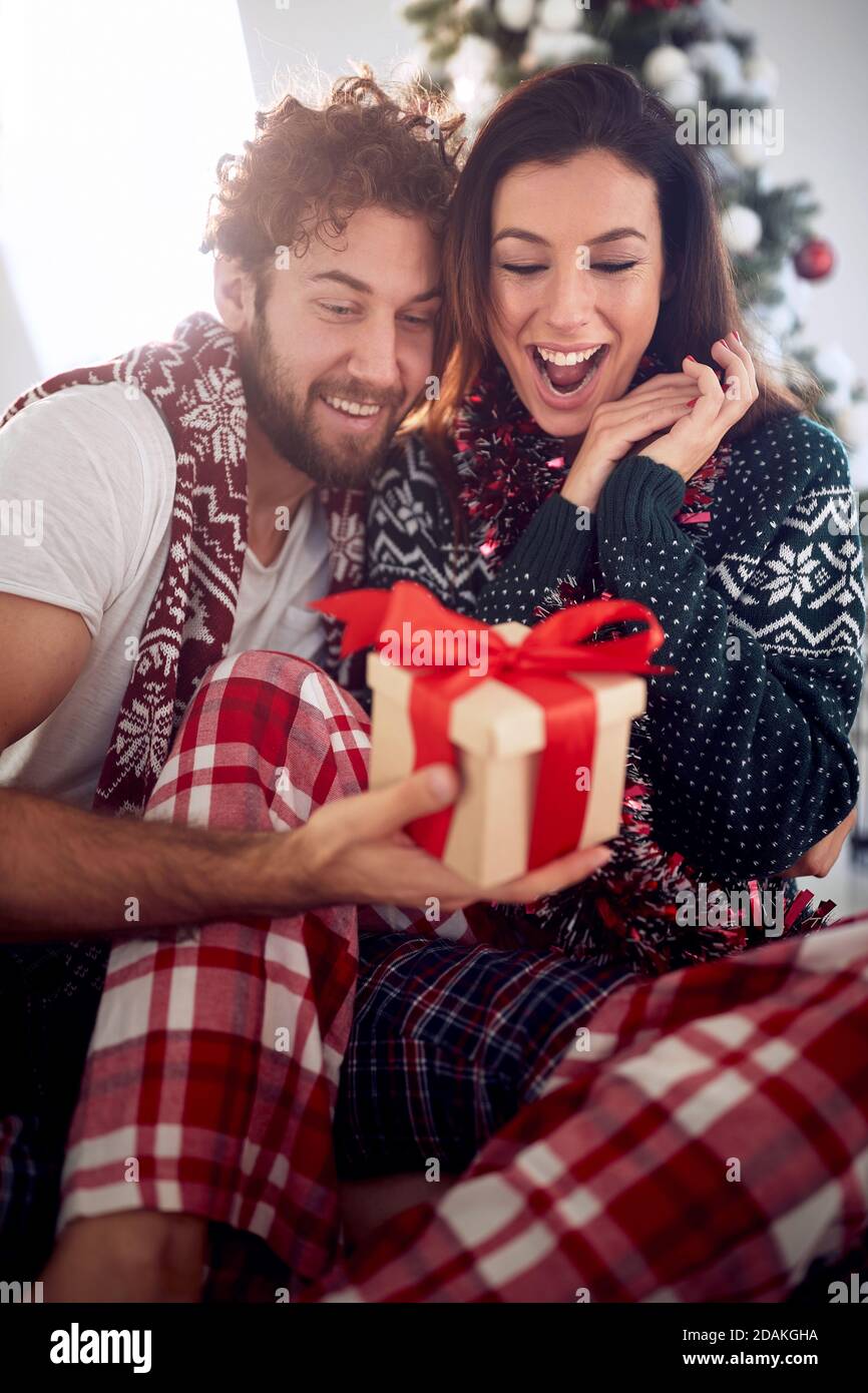 Liebevolles Paar teilt Geschenke am Weihnachtsmorgen zu Hause Stockfoto