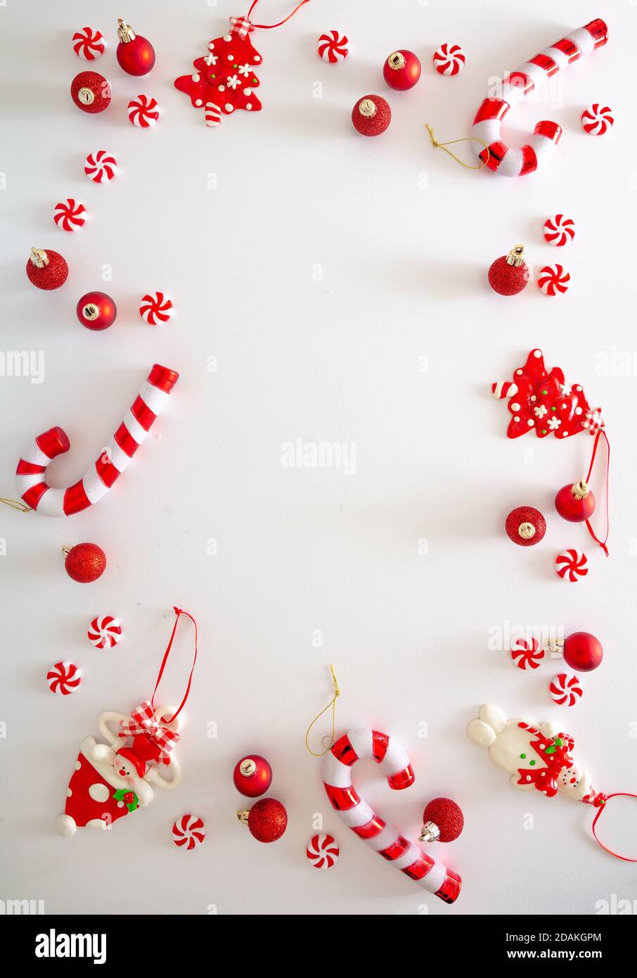 Weihnachtsschmuck Kugeln und süße Bonbons rote Farbe vor weißem Hintergrund, Weihnachtsrahmen flach legen, Urlaub Grußkarte Vorlage, Draufsicht Stockfoto