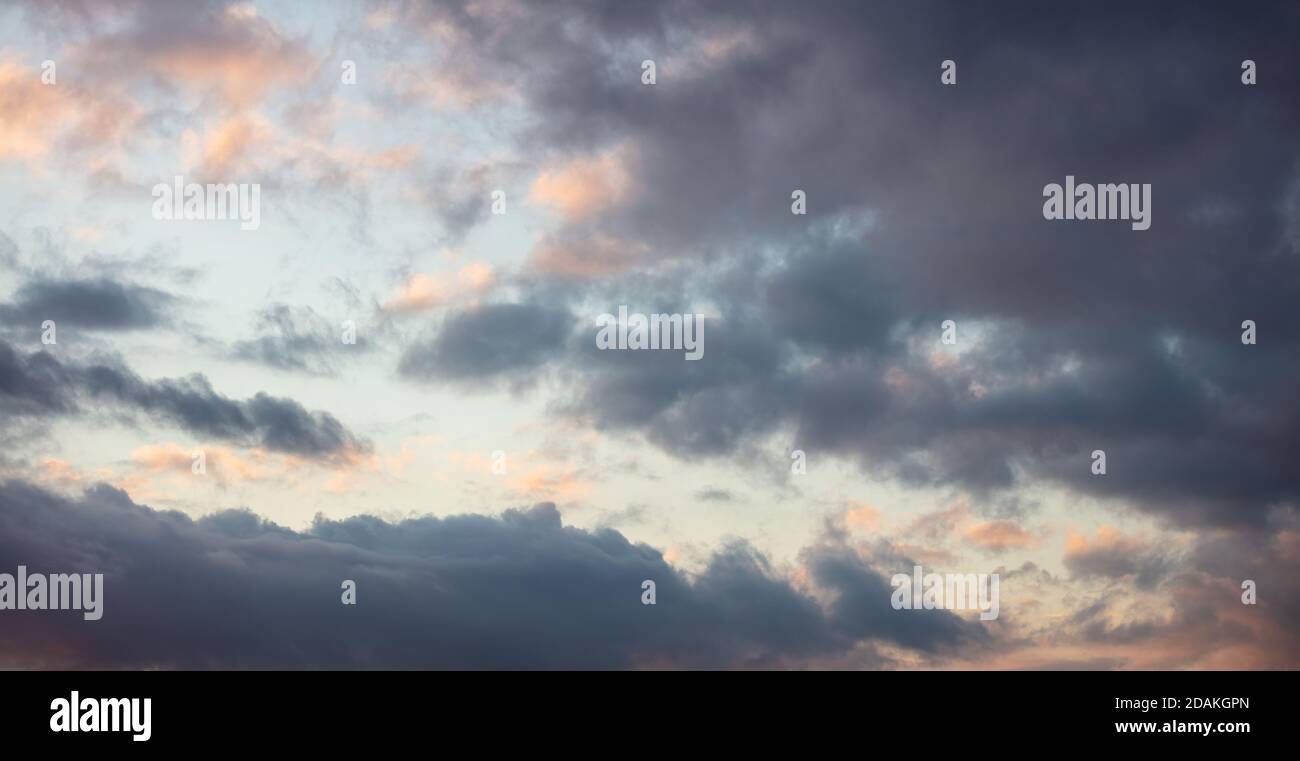 Wolken bei Sonnenuntergang. Dramatische magische Sonnenaufgangswolkenlandschaft über blaugrauem, wolkenbedecktem Himmel Stockfoto