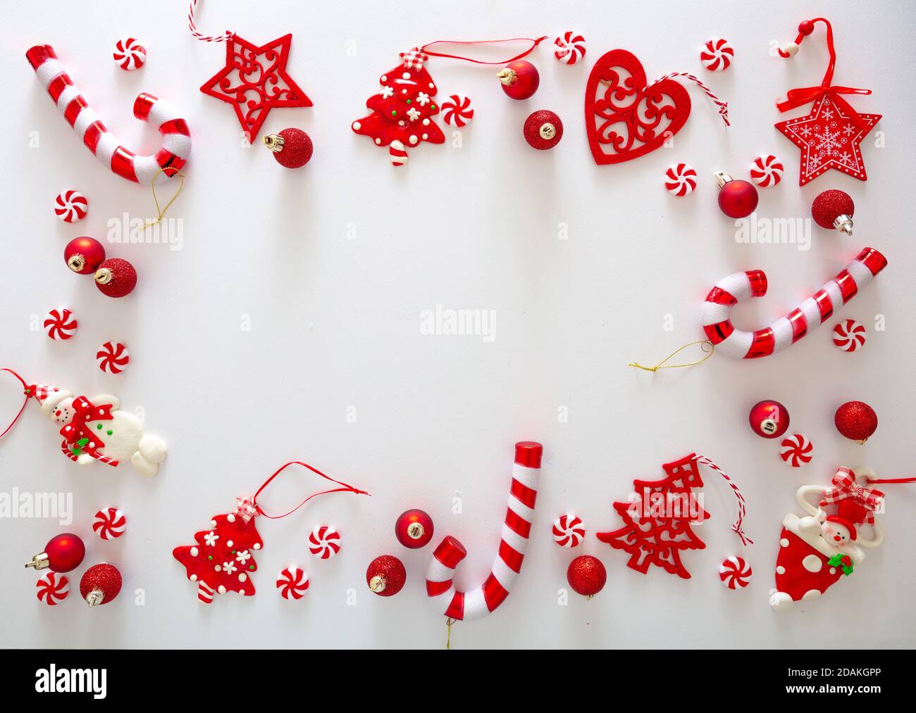 Weihnachtsschmuck Kugeln und süße Bonbons rote Farbe vor weißem Hintergrund, Weihnachtsrahmen flach legen, Urlaub Grußkarte Vorlage, Draufsicht Stockfoto