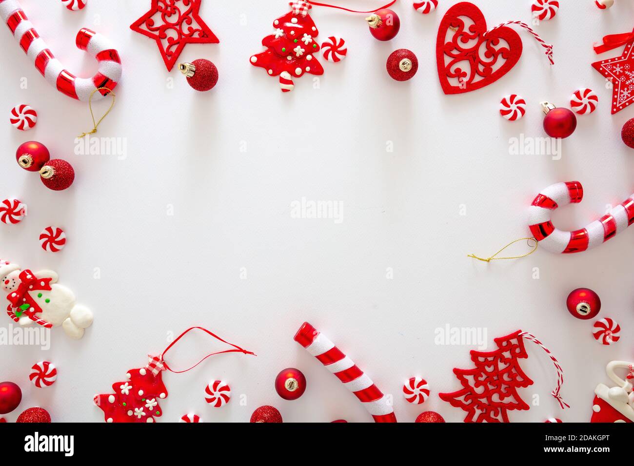 Weihnachtsschmuck Kugeln und süße Bonbons rote Farbe vor weißem Hintergrund, Weihnachtsrahmen flach legen, Urlaub Grußkarte Vorlage, Draufsicht Stockfoto