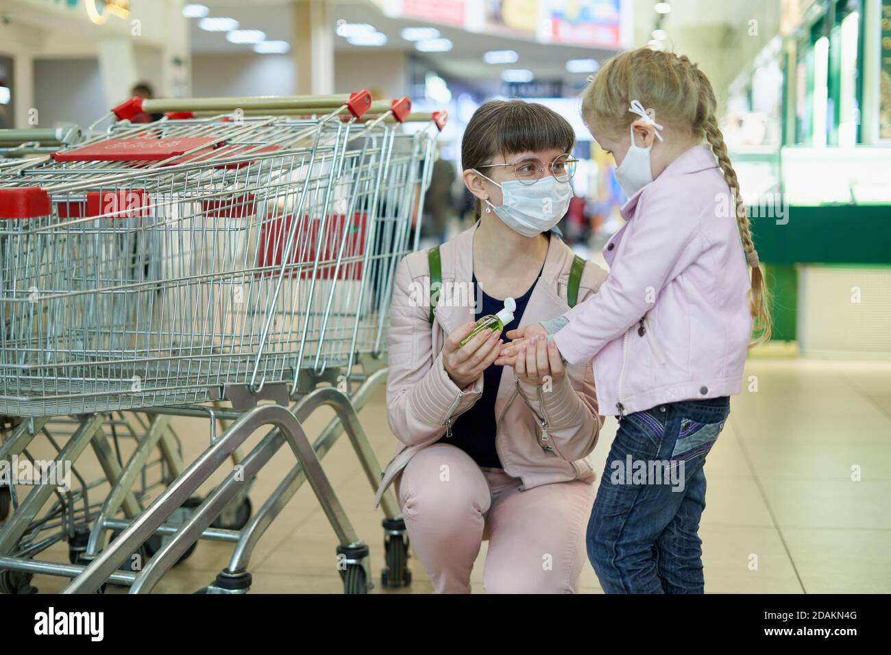 Mama und Kind tragen Schutzmasken tragen Desinfektionsmittel Gel in Ein Einkaufszentrum Stockfoto