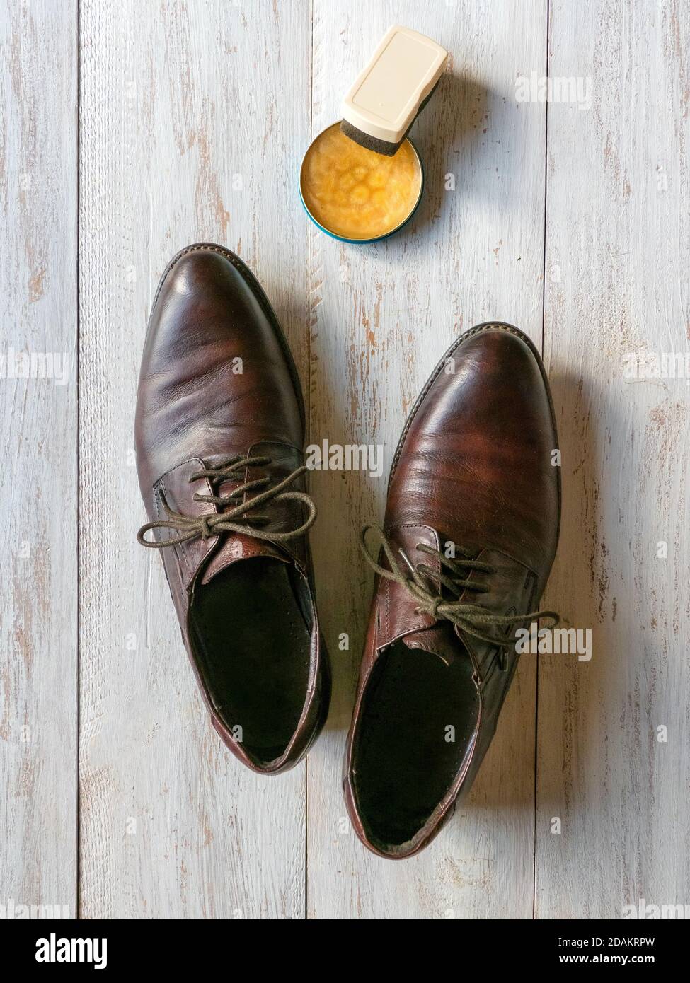 Schutzwachs für Lederschuhe. Konzept für die Schuhpflege. Ein Paar klassische Stiefel auf dem Holzboden. Stockfoto