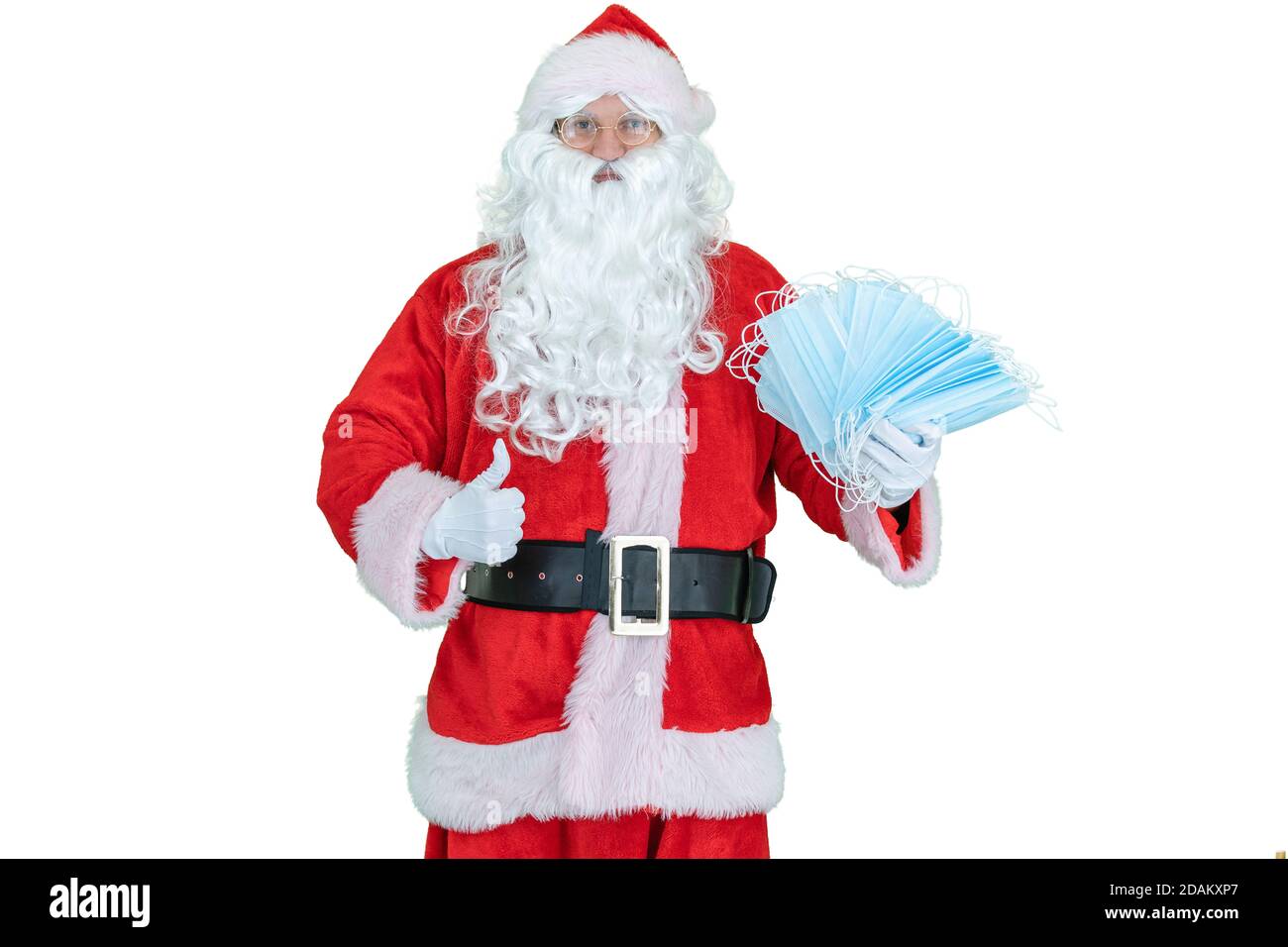 Santa Claus trägt eine covid medizinische Maske, hält Maske oder Atemschutzmasken Epidemie oder Coronavirus Schutz. Der Weihnachtsmann zeigt den Daumen nach oben Stockfoto
