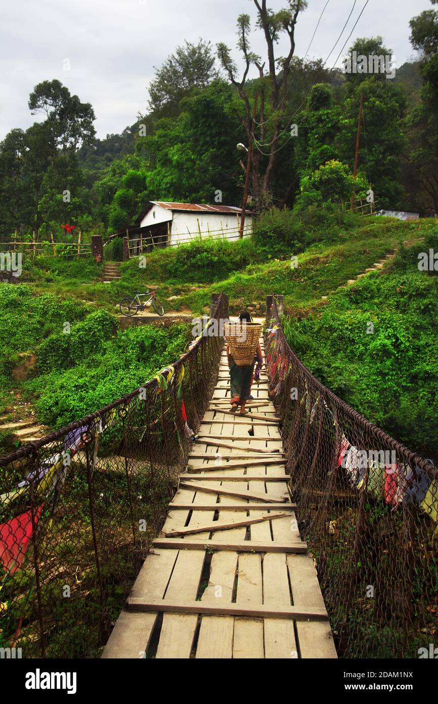 Frau mit Korb über Hängebrücke über einem Pardi Khola Fluss. Pokhara, Nepal Stockfoto