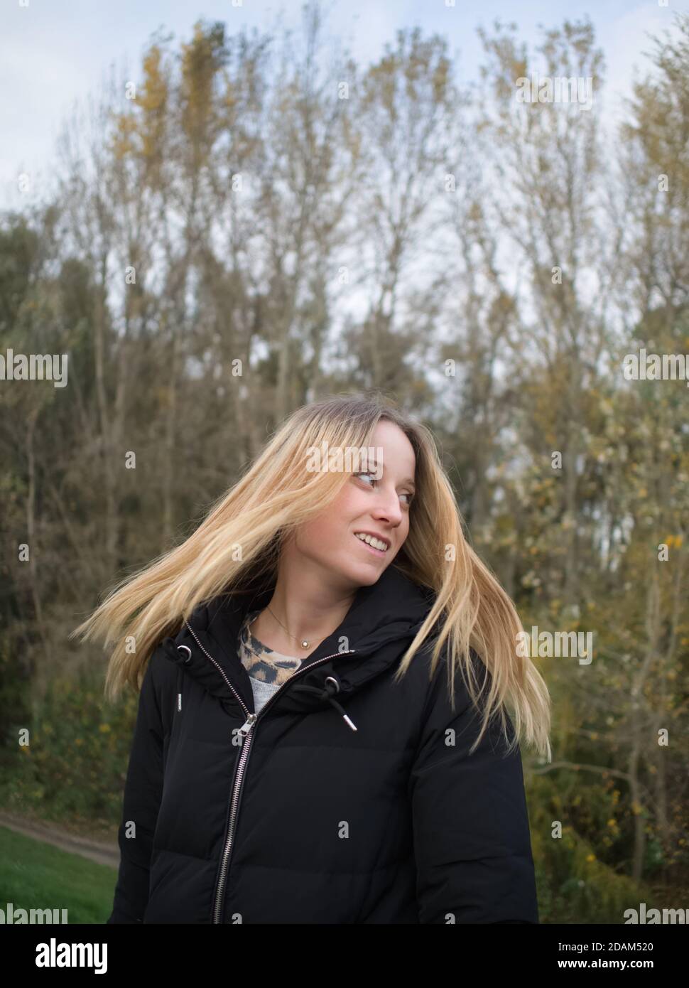 Schöne junge Frau wirft ihr langes blondes Haar im Herbst Parken Stockfoto