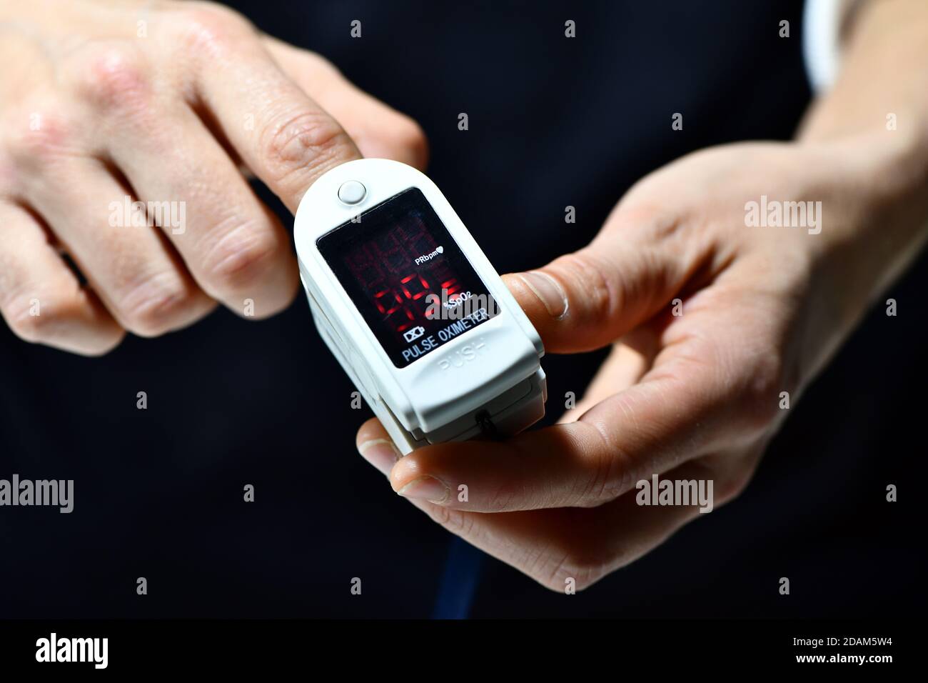 Eine Frau misst Sauerstoff in ihrem Blut mit einem nicht gebrandeten Oximeter Stockfoto