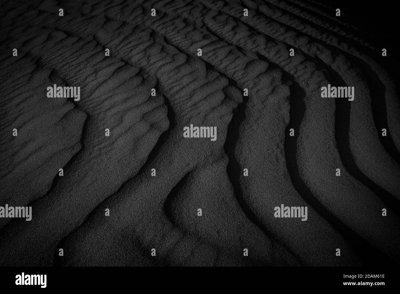 Makrofotografie mit schwarzem und weißem Sand am Strand. Textur von schwarz und whote Sand für den Hintergrund. Nahaufnahme Makroansicht der vulkanischen Sandoberfläche schwarz und w Stockfoto