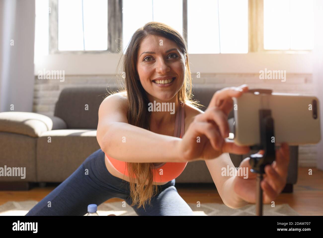 Personal Trainer macht Fitnessunterricht per Smartphone. Sie ist zu Hause wegen Coronavirus codiv-19 Quarantäne Stockfoto