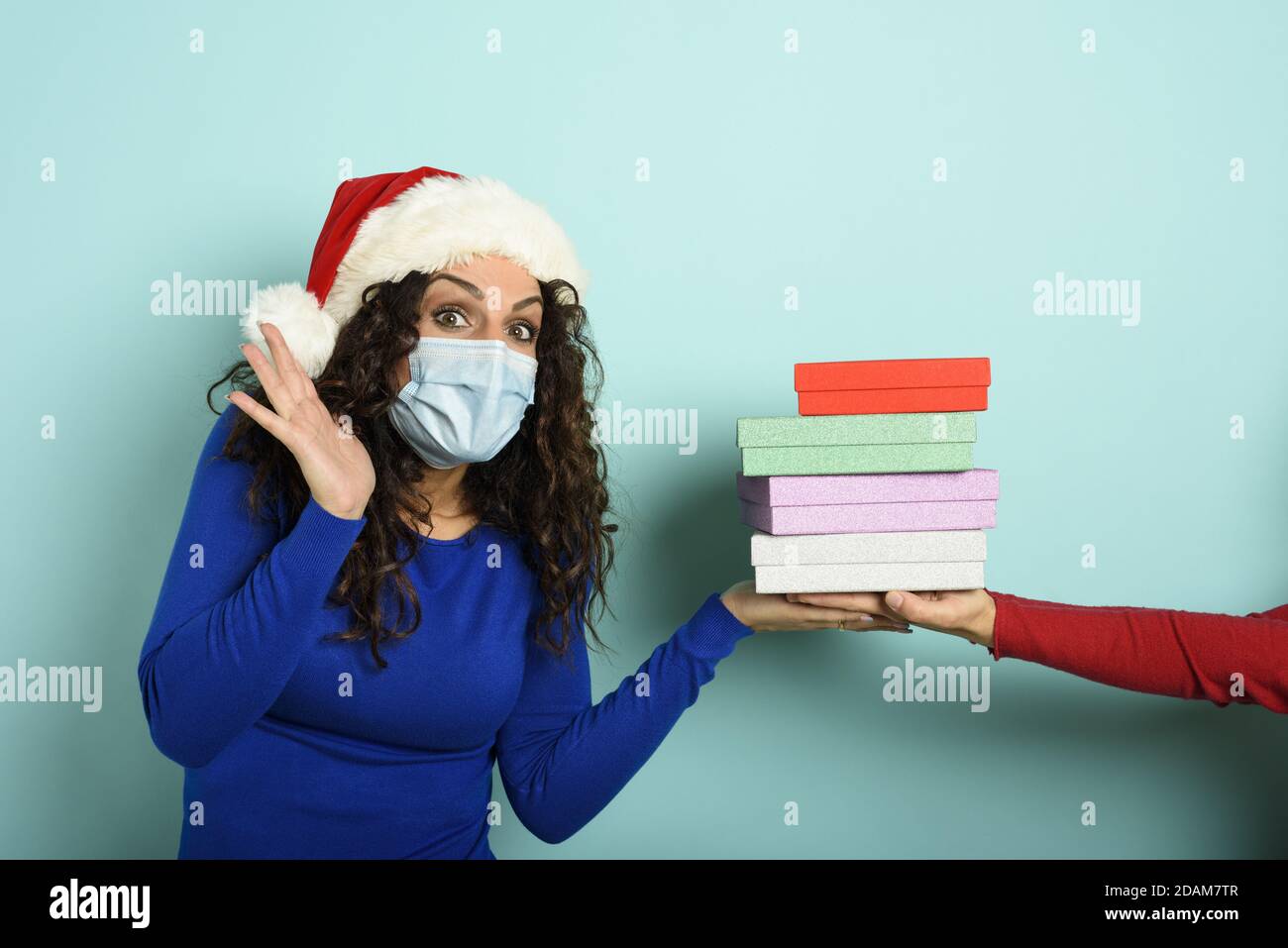 Glückliches Mädchen mit Gesichtsmaske erhält Weihnachtsgeschenke. Cyan Hintergrund Stockfoto