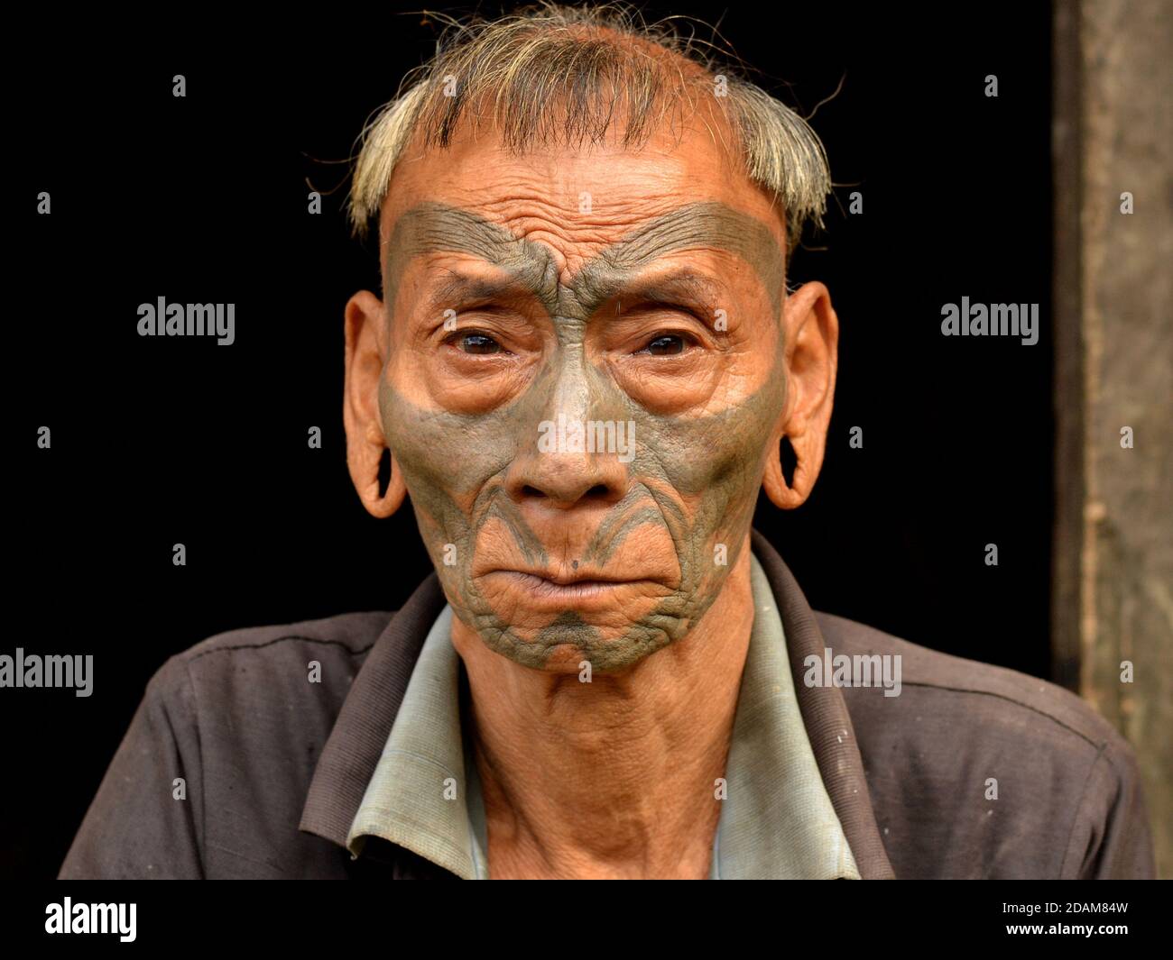 Alt pensionierten indischen Konyak Naga Krieger und Ex-Headhunter mit unverwechselbaren Tribal Gesichts-Tattoo und traditionelle Frisur Posen für die Kamera. Stockfoto