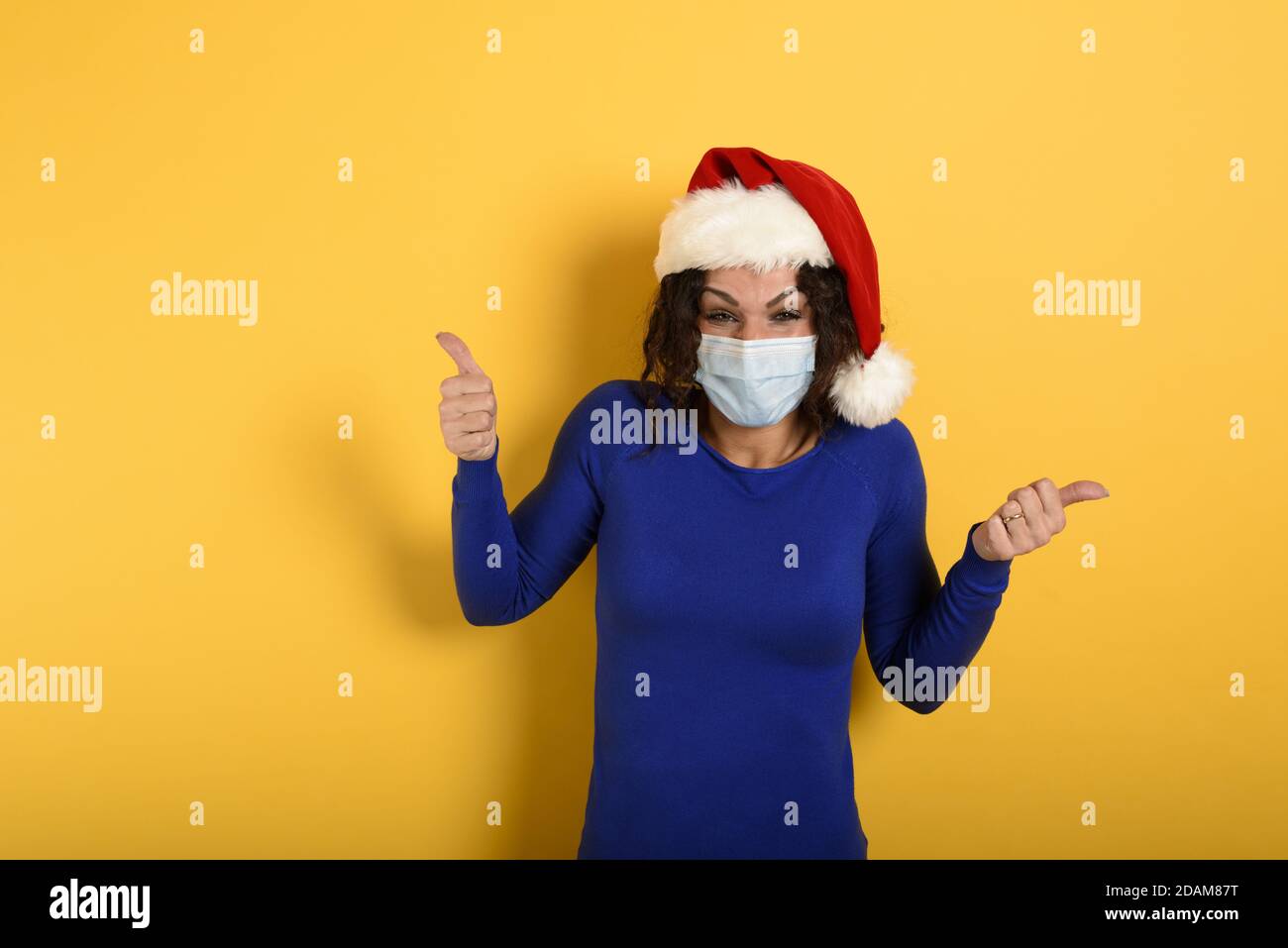 Mädchen mit weihnachtshut ist optimistisch über die Niederlage der covid 19 Coronavirus. Cyan Hintergrund. Stockfoto