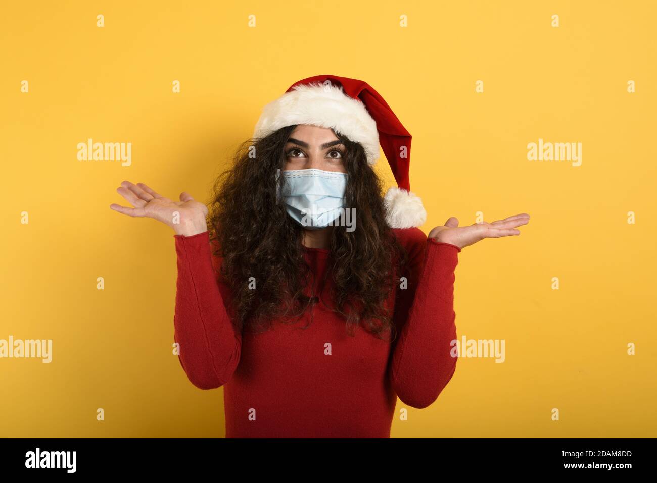 Frau mit Gesichtsmaske ist über etwas gewundert. Gelber Hintergrund Stockfoto