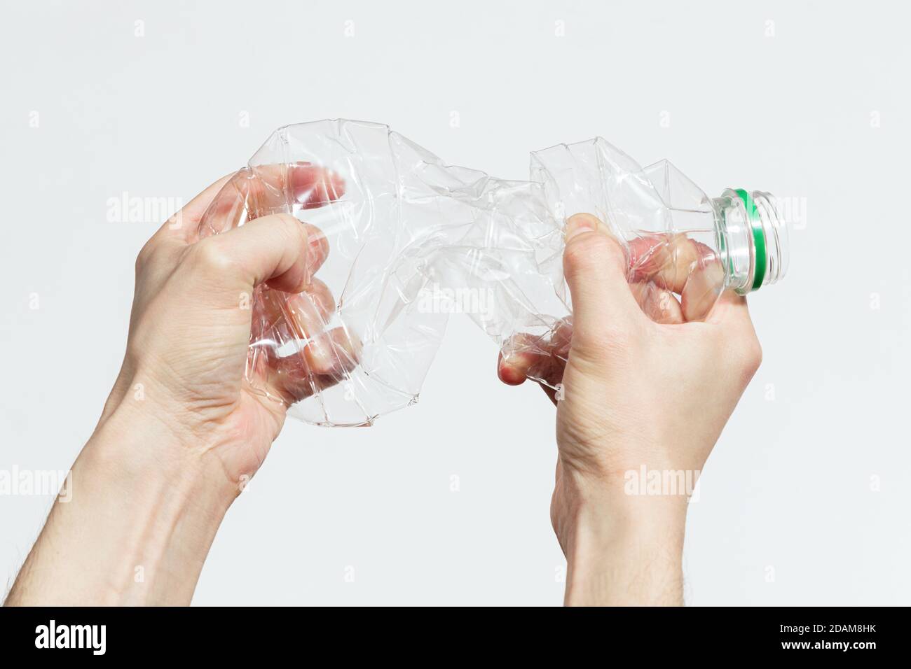 Mann zerschlug eine Plastikflasche mit seinen Händen auf weiß Hintergrund Stockfoto