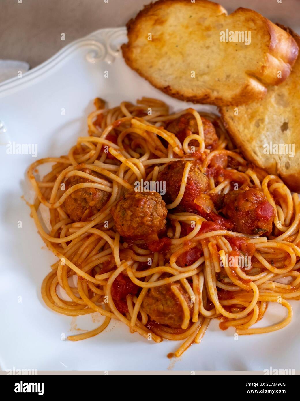 Gekochte Spaghetti und Fleischbällchen auf einem weißen Teller mit geröstetem Knoblauchbrot. Nahaufnahme. Stockfoto