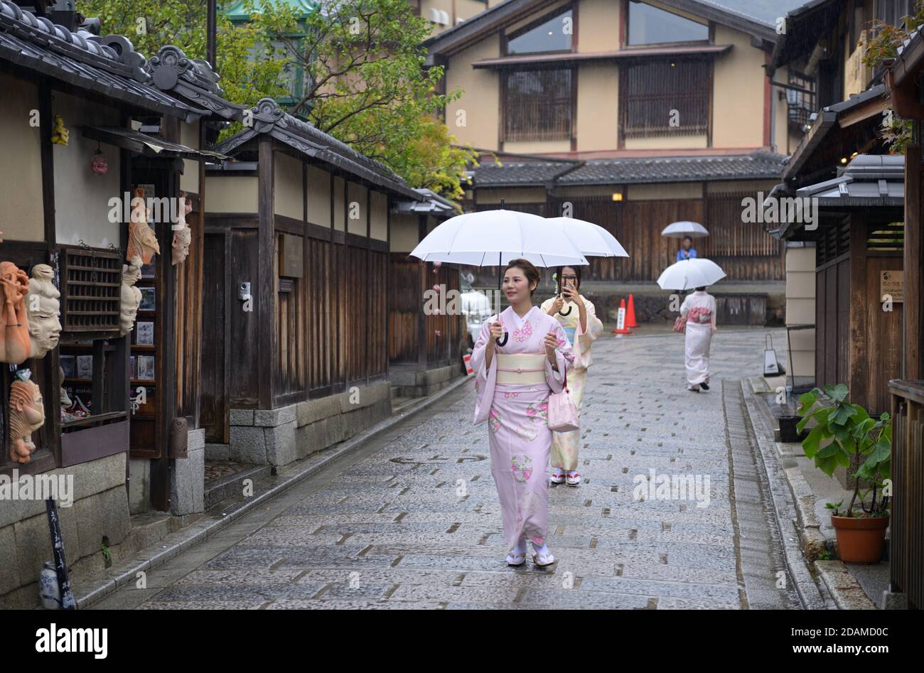 Japanische Frauen in Kimonos, die im historischen Gion, Kyoto JP, unter dem Regen spazieren Stockfoto