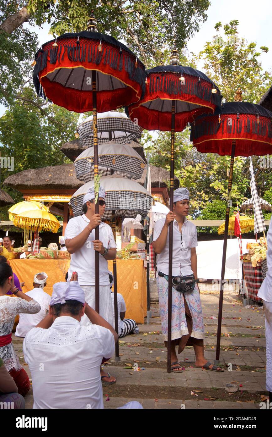 Balinesische Männer mit handgefertigten Sonnenschirmen im Sakenan Tempel während Galungan Feierlichkeiten, Bali, Indonesien Stockfoto
