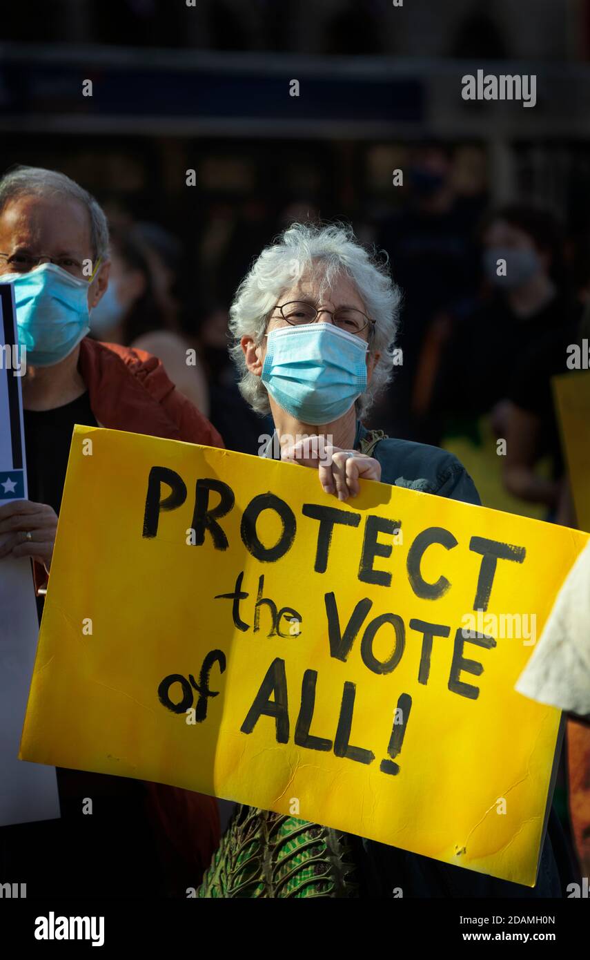 Copley Square, Boston, Massachusetts, USA, 7. November 2020. Eine Reihe von Gemeinschaftsorganisationen versammelten sich, um den Schutz der Demokratie zu fordern und jede Stimme bei den Wahlen 2020 zu zählen. Das Foto zeigt ein Paar mittleren Alters, das während der Demonstration Schilder hält. Alle bei der Demonstration waren verpflichtet, eine Gesichtsbedeckung oder Maske zu tragen und nach Möglichkeit soziale Distanz zu erreichen. Stockfoto