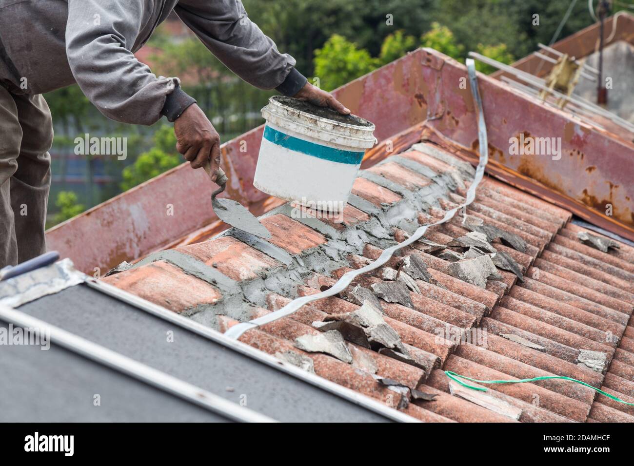 Asiatische Arbeiter sichern Dachziegel mit Zement auf dem alten Gebäude Stockfoto