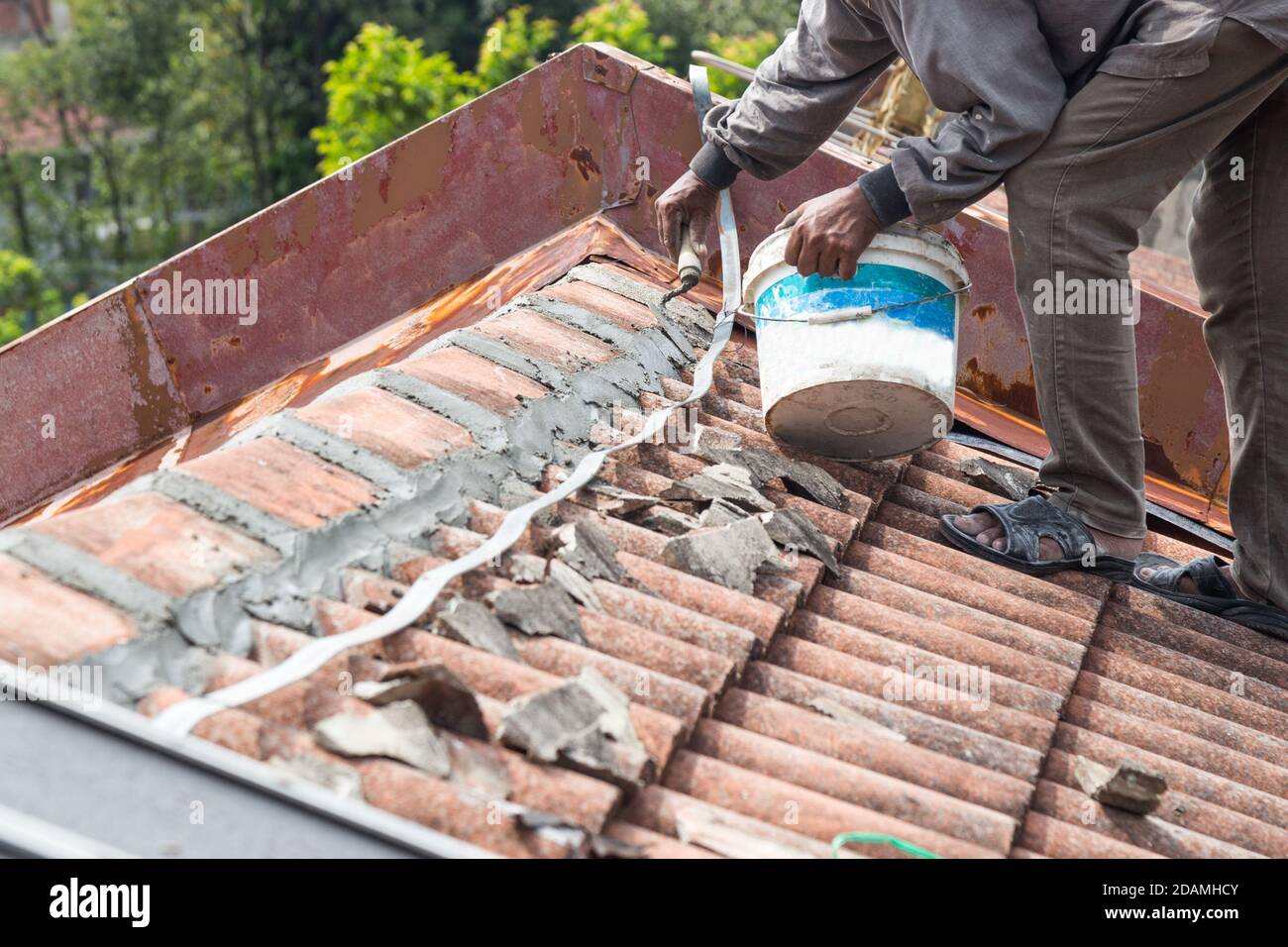 Asiatische Arbeiter sichern Dachziegel mit Zement auf dem alten Gebäude Stockfoto