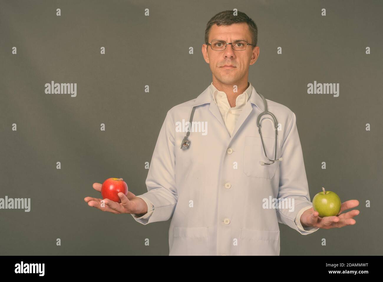 Schöner mann Arzt mit kurzen Haaren gegen grauer Hintergrund Stockfoto