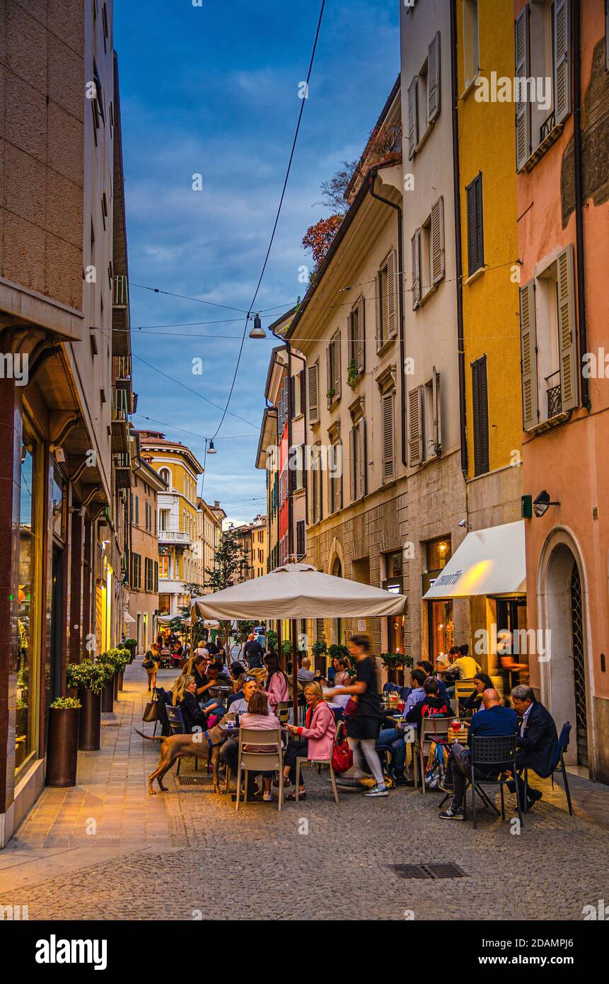 Brescia, Italien, 10. September 2019: Typisch italienische schmale Straße mit traditionellen alten Gebäuden und Straßenrestaurant mit Menschen zum Abendessen, historisches Zentrum, Abenddämmerung Blick, Lombardei Stockfoto