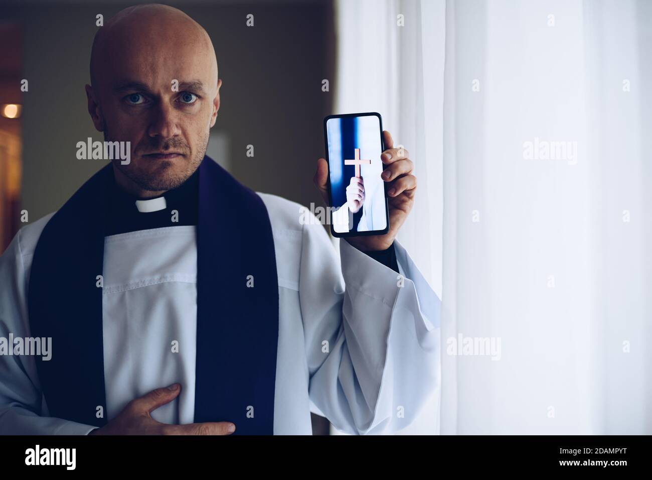 Junger Priester mit Mobiltelefon. Stockfoto