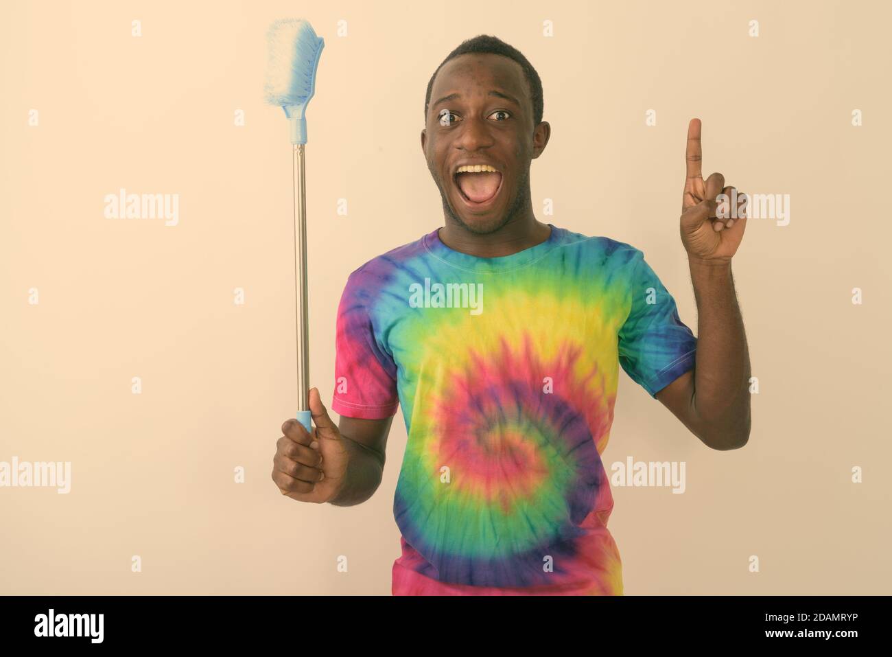 Studio-Aufnahme von jungen schwarzen afrikanischen Mann suchen aufgeregt und Glücklich, während Sie die Reinigungsbürste halten und den Finger nach oben zeigen Weißer Hintergrund Stockfoto
