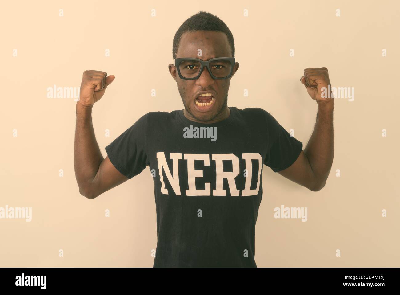 Studio-Aufnahme von jungen schwarzen afrikanischen Geek Mann trägt Nerd shirt, während er seine Arme beugt und Bizeps gegen Weiß zeigt Hintergrund Stockfoto