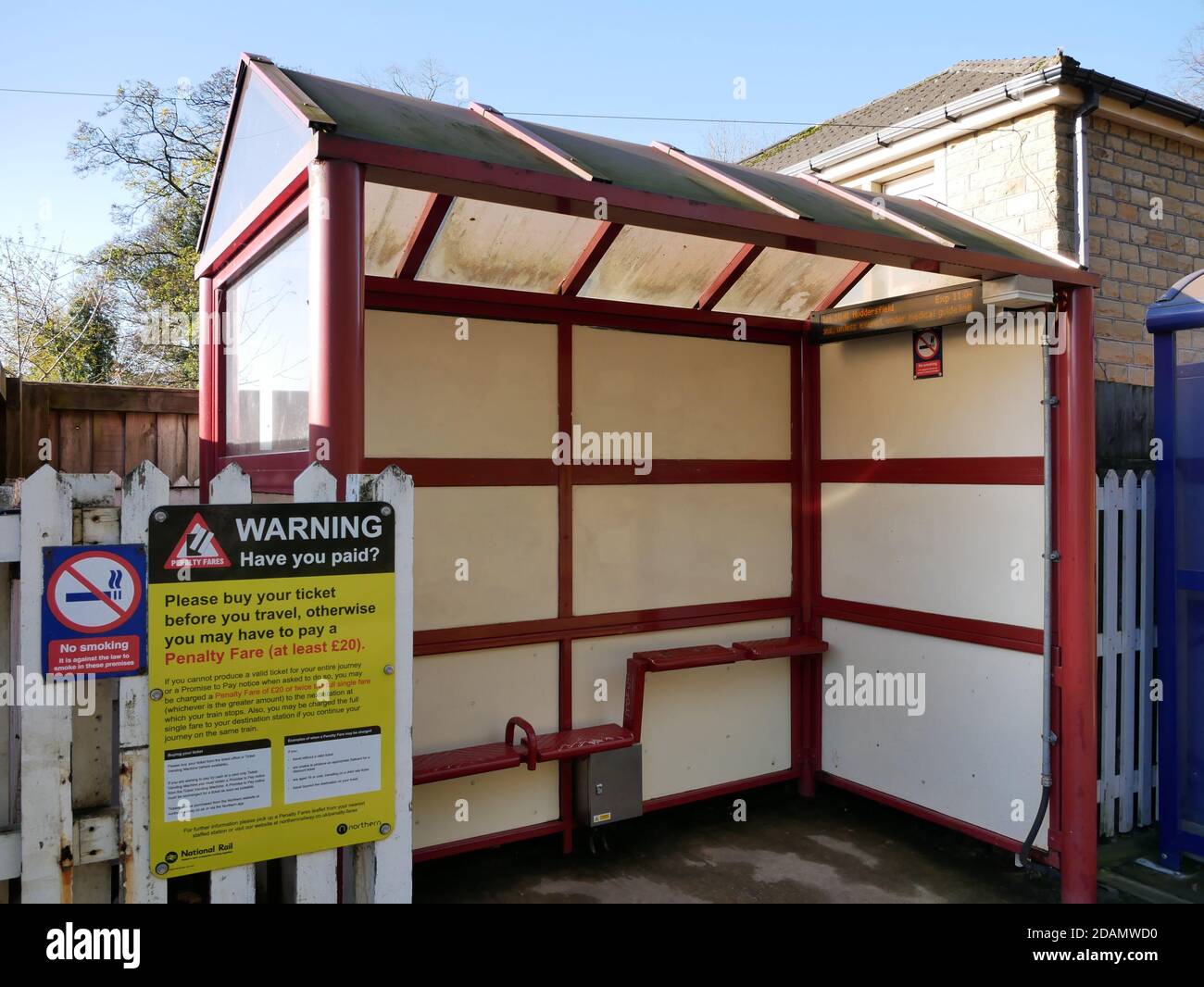 Rot und weiß Bahnhofsplatz Bahnsteig Schutz mit Glasdach Und kleine rote Sitze und Warnschild Stockfoto