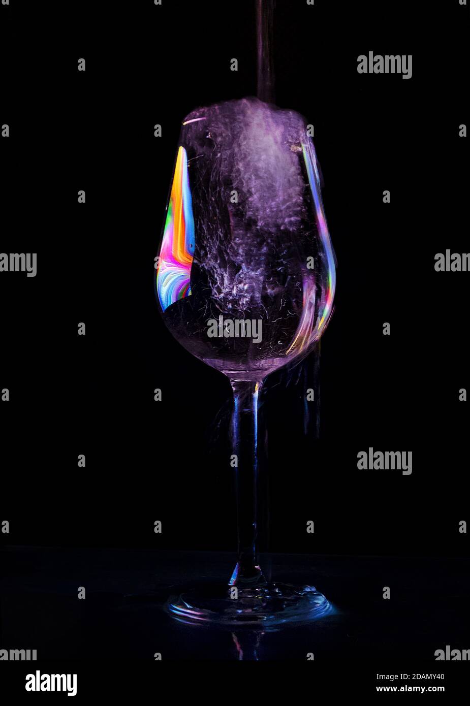 Wein in eine Glasschale auf schwarzem Hintergrund gegossen Stockfoto