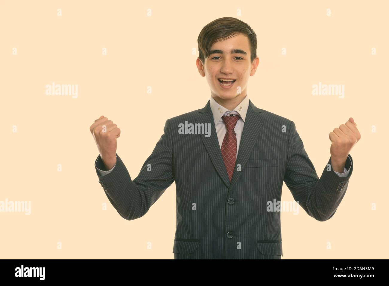 Studioaufnahme des jungen glücklichen persischen Teenager-Geschäftsmann lächelnd während Freuen Sie sich Stockfoto