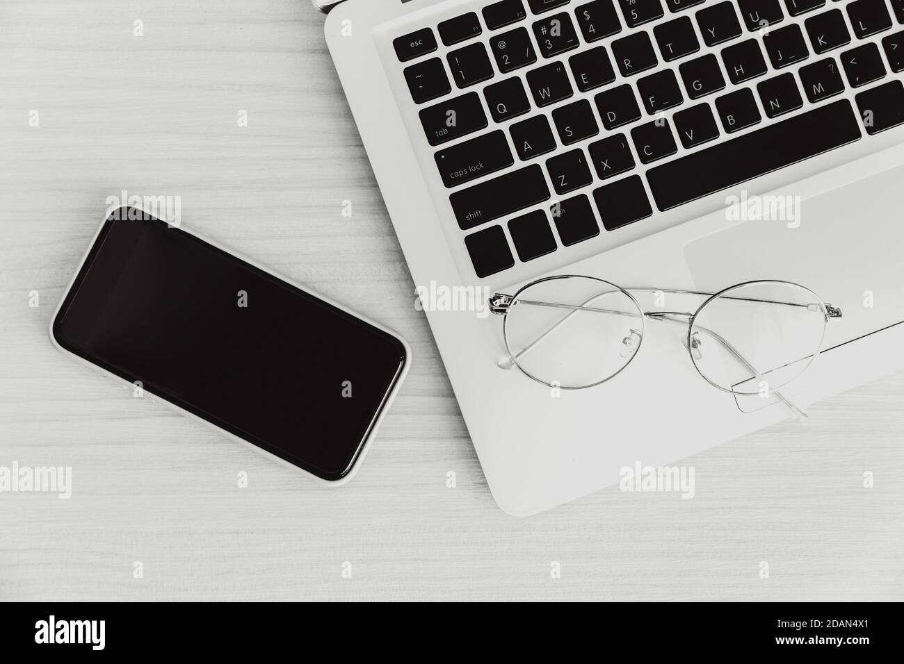 Laptop-Computer auf dem Schreibtisch mit Smartphone und Brille Draufsicht monoton für minimale Business flach Lay Bild. Stockfoto