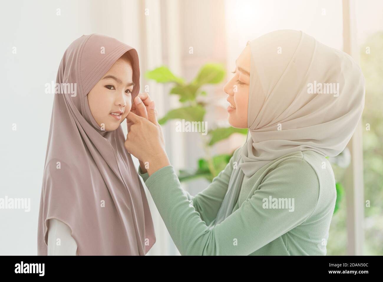 Muslimische oder islamische Mutter, die morgens ihr Hijab für ihre Tochter zu Hause kleidet. Stockfoto