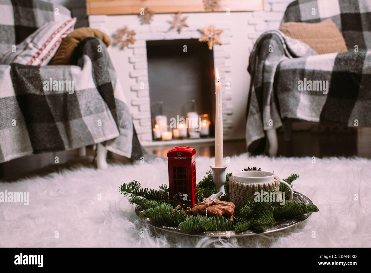 Eine Tasse heißen Kräutertee auf einem eisernen Tablett mit Christbaumzweigen, brennenden Kerzen, Zapfen, Keksen, Spielzeug. Weihnachten Hintergrund. Neujahr Stockfoto