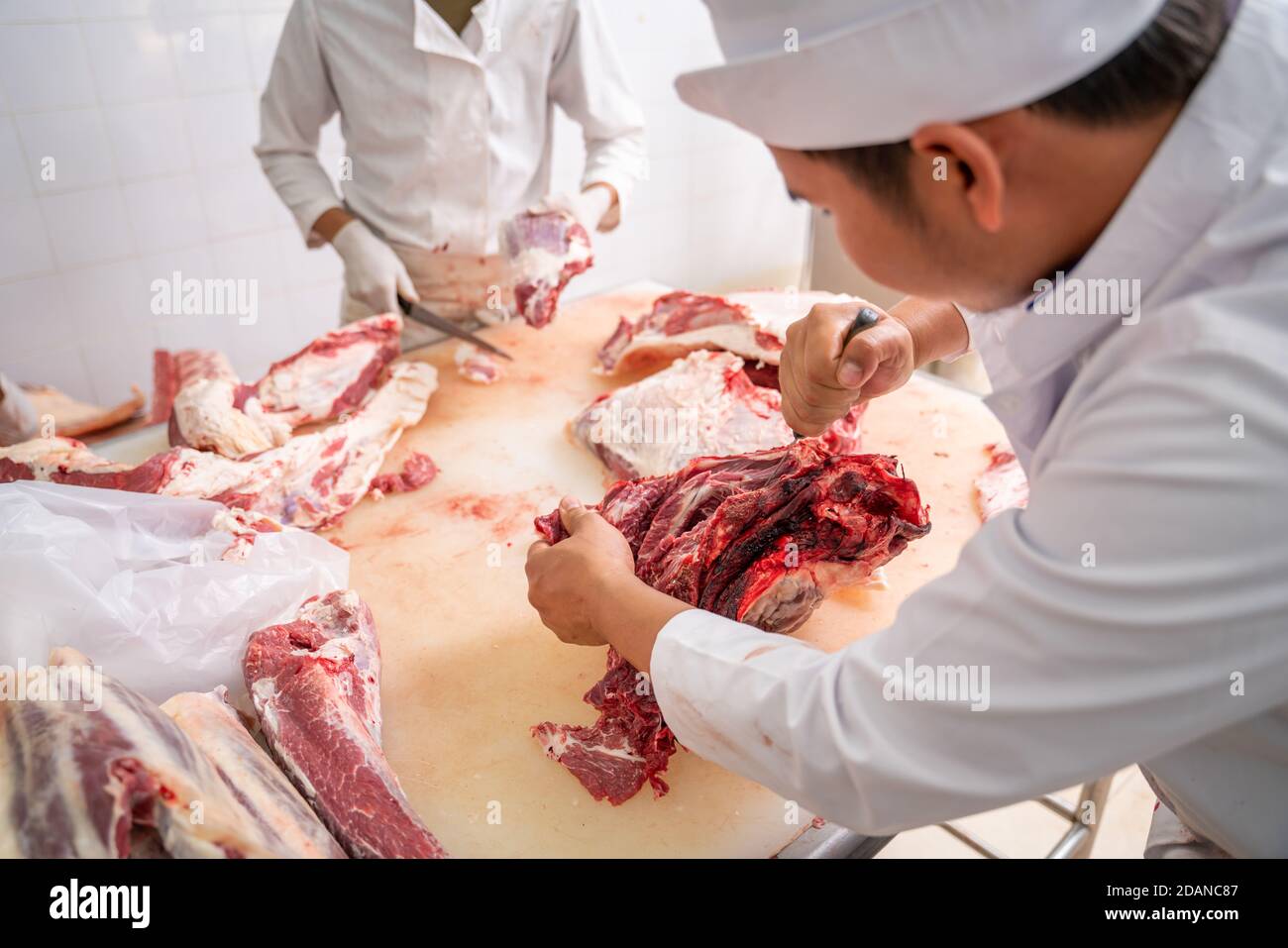 Asiatische Metzger schneiden rohes Fleisch Wagyu Rindfleisch mit einem Messer im Schlachthof, Fleischindustrie, Wagyu Rindfleisch Stockfoto