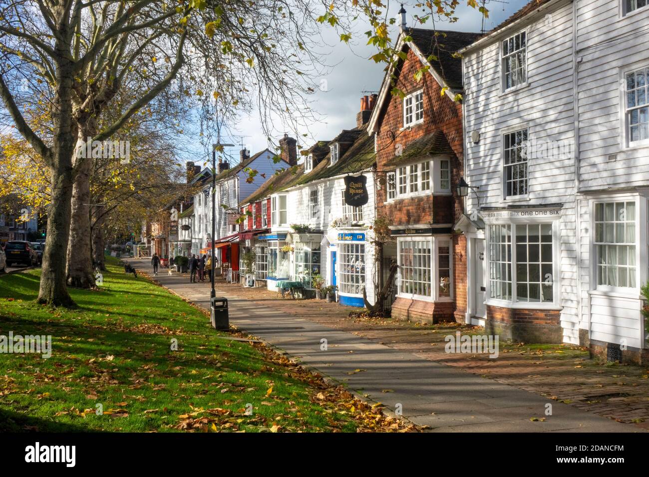 Tenterden, Leute in Cafés mit Tischen im Freien, an eleganten Geschäften auf dem malerischen breiten Bürgersteig der von Bäumen gesäumten High Street, Kent, Großbritannien Stockfoto