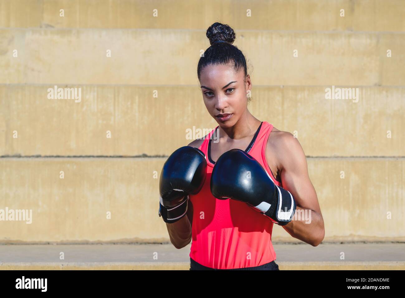 Horizontales Porträt einer attraktiven afrikanischen Frau in Sportkleidung Und Boxhandschuhe stehen in Verteidigungspose Stockfoto