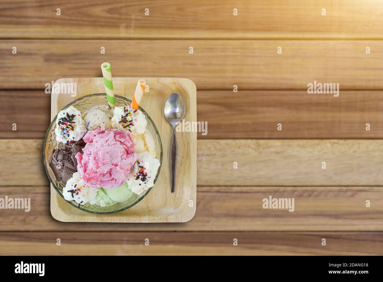 Schüssel mit Eisschaufeln in verschiedenen Farben und Geschmacksrichtungen auf Holz Hintergrund. Selektiver Fokus Stockfoto