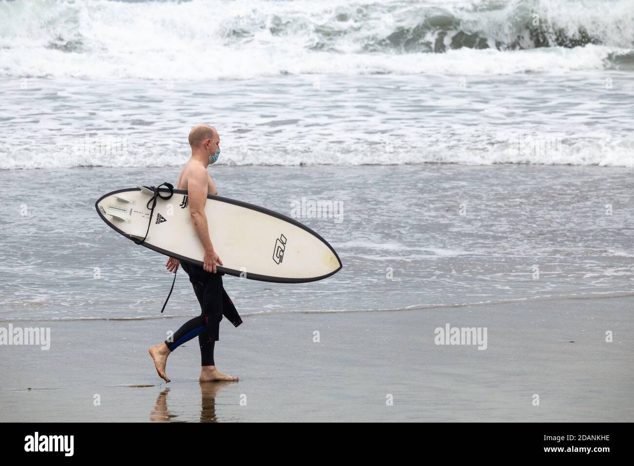 Las Palmas, Gran Canaria, Kanarische Inseln, Spanien. November 2020. Surfer mit Gesichtsbedeckung am Stadtstrand in Las Palmas auf Gran Canaria. Ab dem 23. November müssen Personen, die von Hochrisiko-Destinationen (einschließlich Großbritannien) auf die Kanarischen Inseln kommen, innerhalb von 72 Stunden vor ihrer Ankunft in Spanien ein negatives Covid-Ergebnis vorbringen. Kredit: Alan Dawson/Alamy Live Nachrichten Stockfoto