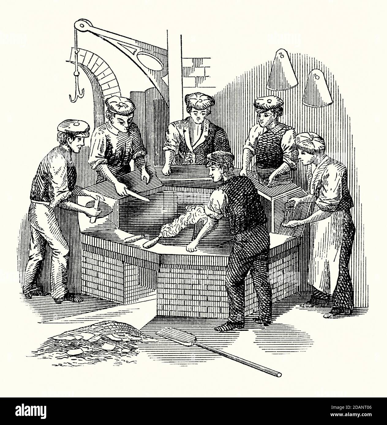 Eine alte Gravur, die Männer zeigt, die an einer Batterie eines Hatmaker arbeiten, die bei der Herstellung von Filzhüten verwendet wird. Es ist aus einem viktorianischen Maschinenbaubuch der 1880er Jahre. Die Batterie ist ein Kessel oder Wasserkocher mit heißem Wasser, plus eine kleine Menge Schwefelsäure. Die Säure hilft dem Fell, sich leichter ‘zu verfilzen’, wenn es an den konischen Hutkörpern haftet. Ein ‘Nickerchen’ ist die erhöhte (verschwommene) Oberfläche auf Tüchern wie Samt oder Moleskin, oder die Oberfläche von Filz oder Biberpelz. Die Arbeiter unterstützen diesen Nickvorgang, indem sie mit ihren Holzwerkzeugen, den ‘Handschuhen’, reiben. Stockfoto