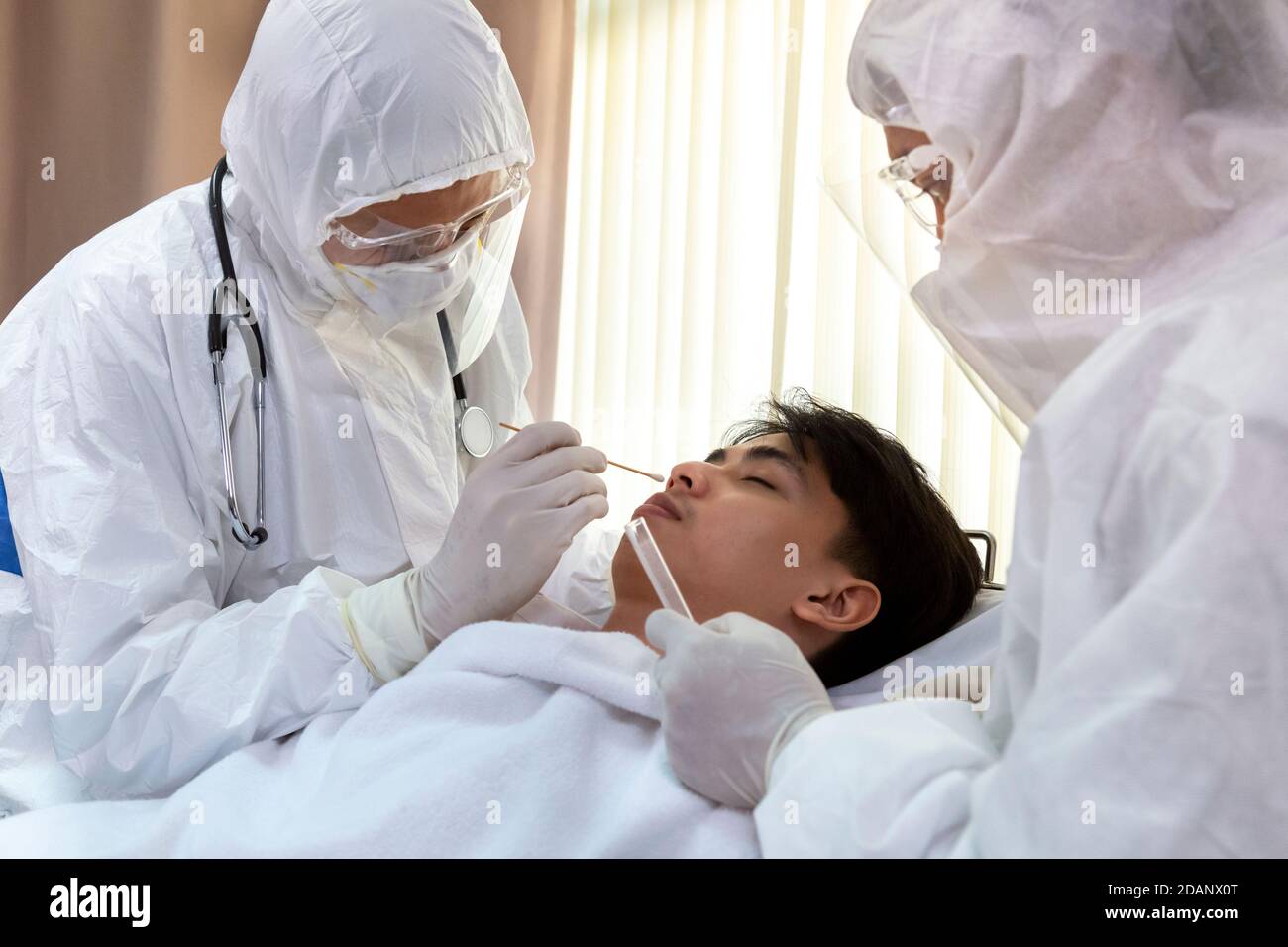 Krankenschwester und Arzt tragen psa Anzug und Gesichtsmask führen Coronavirus COVID-19 PCR-Test. Patient nasalen NP und oralen OP-Tupfer Probe Collectio Stockfoto