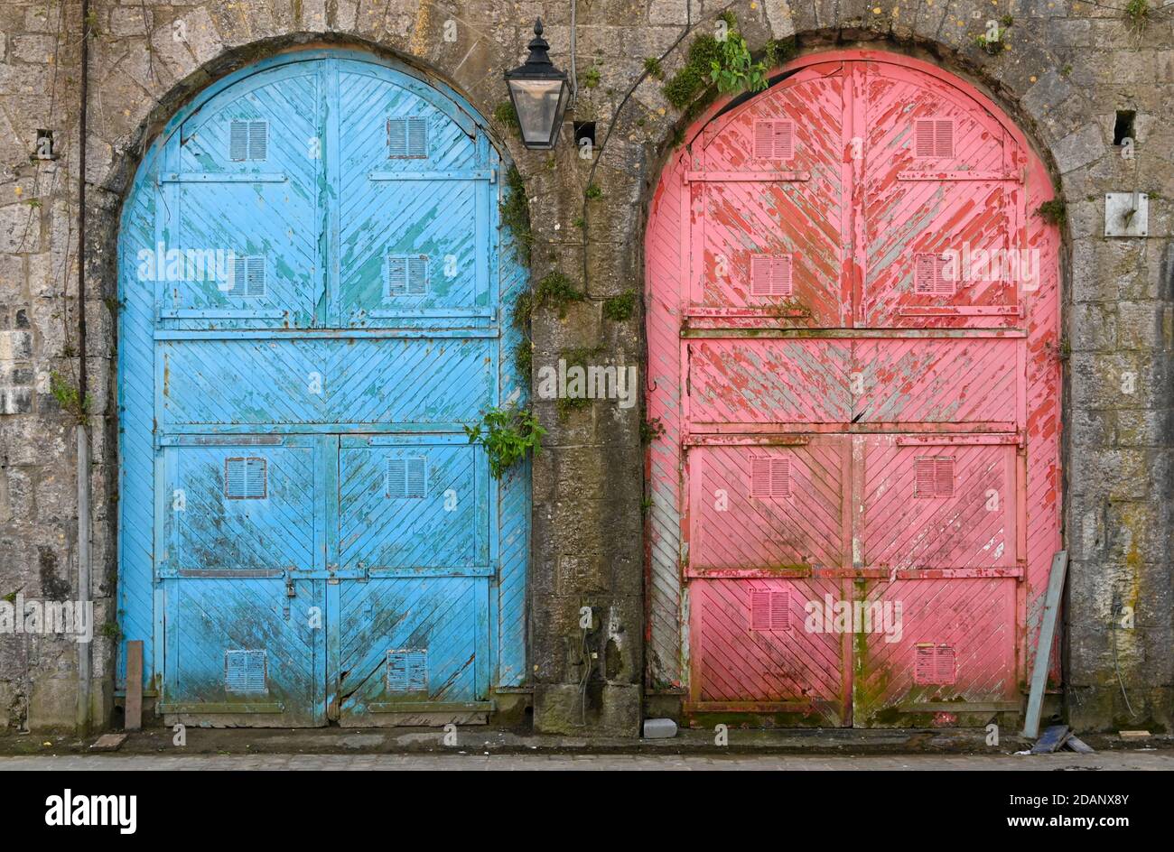 Zwei große bunte alte Türen mit abblätternder Farbe in einem Steingebäude. Stockfoto